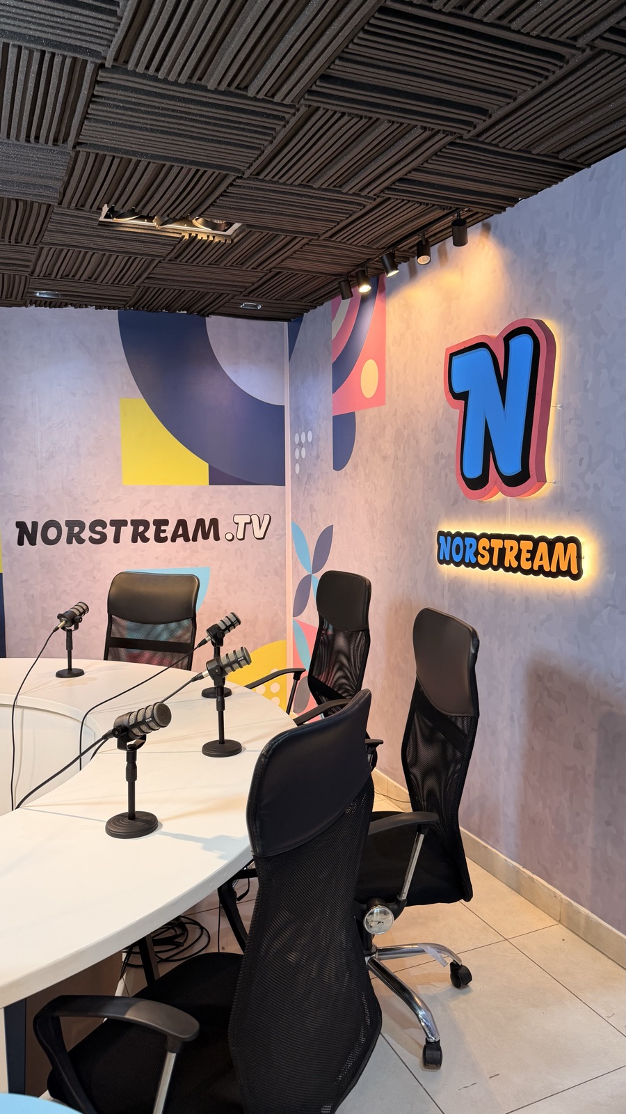 Set de Norstream TV: mesa de programas, micrófonos y cartel luminoso